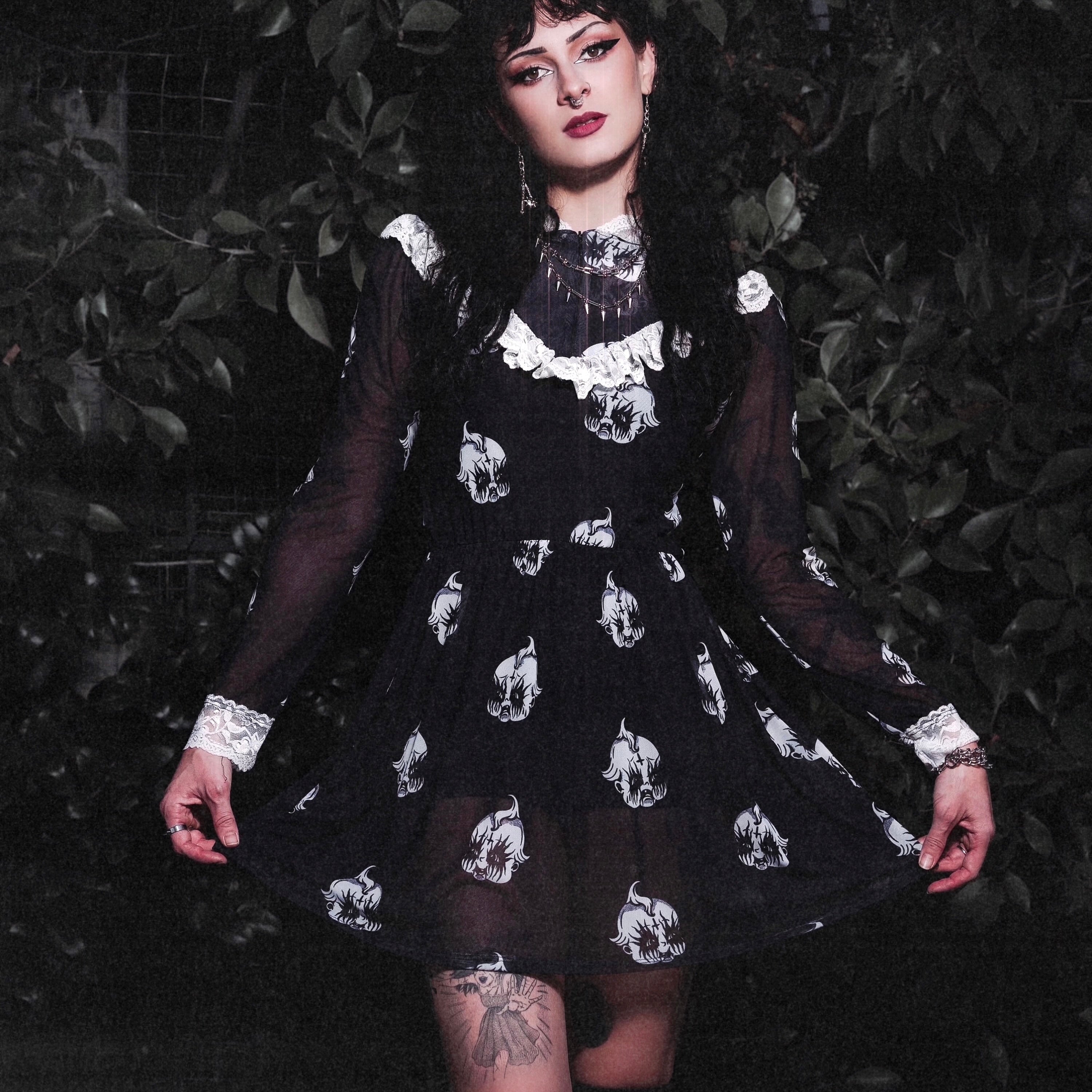 Person wearing a black dress with white patterns against a dark background