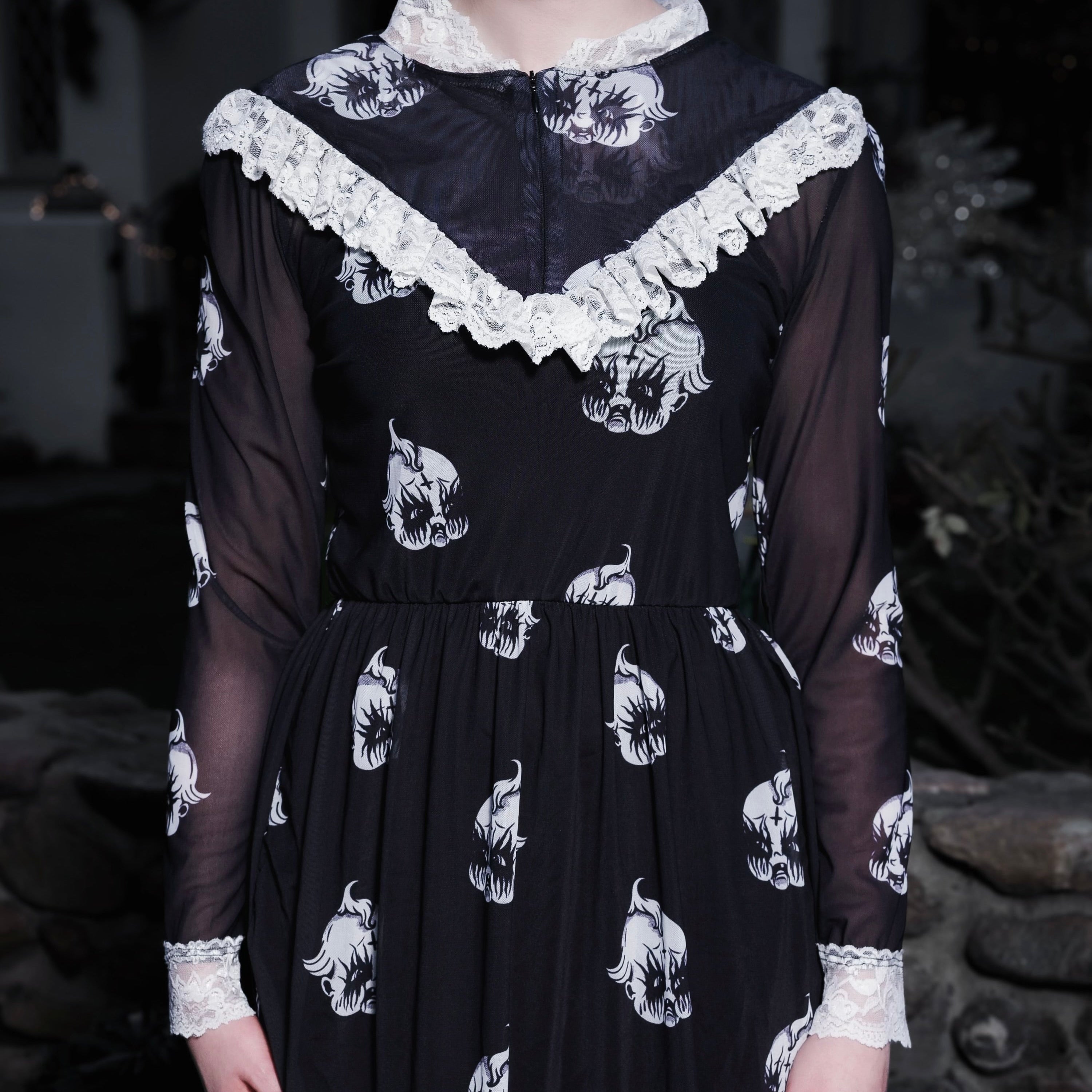 Black dress with white floral patterns worn by a person in a dark setting