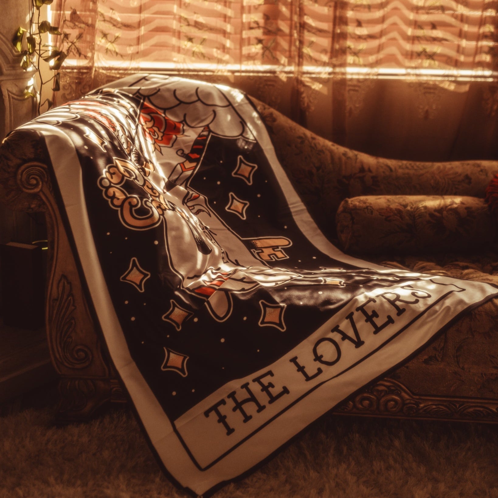 Decorative scarf with tarot card design draped over a chair in a warm-toned room.