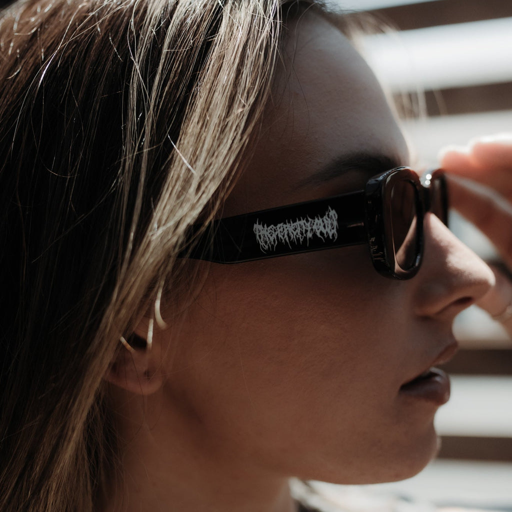Person wearing sunglasses with a brand logo, sitting inside a vehicle.