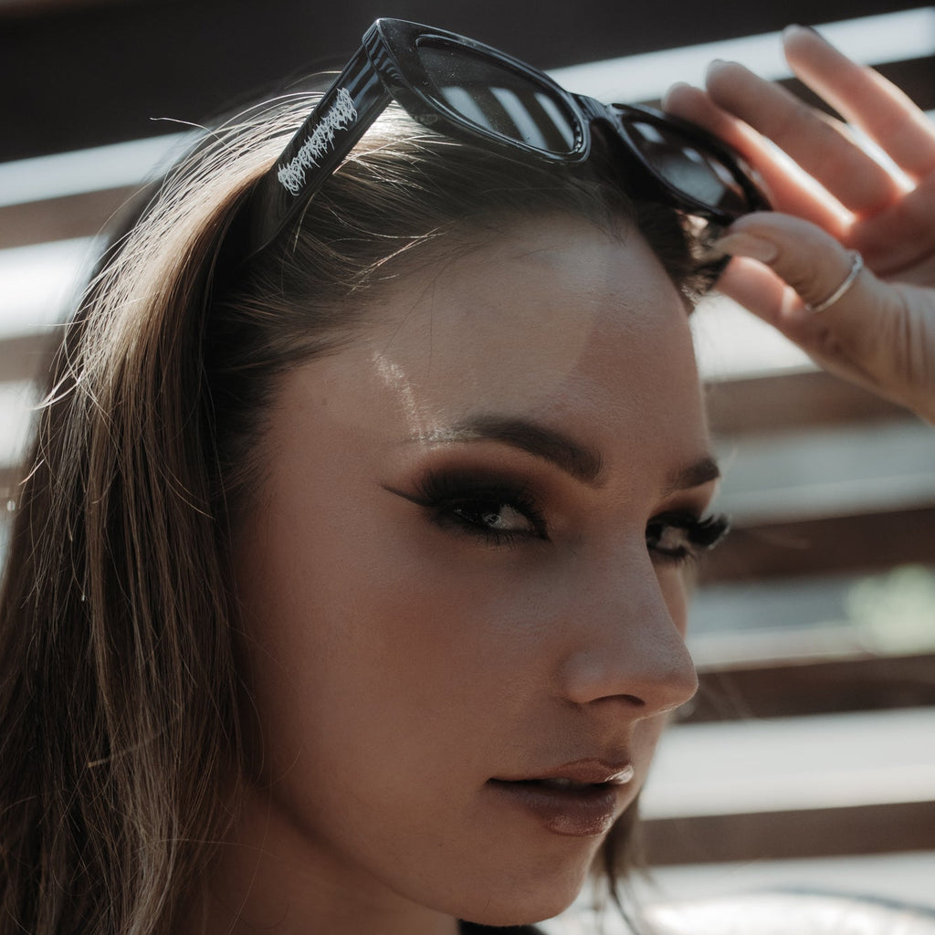 Woman adjusting sunglasses with a blurred background