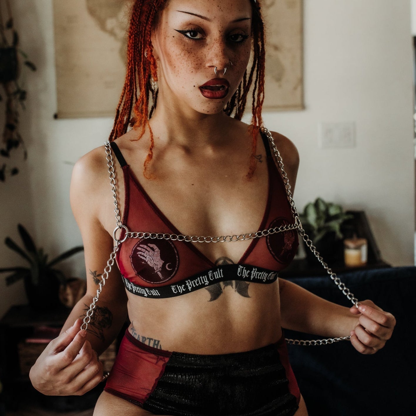 Person wearing a red and black bikini with chain details in an indoor setting.