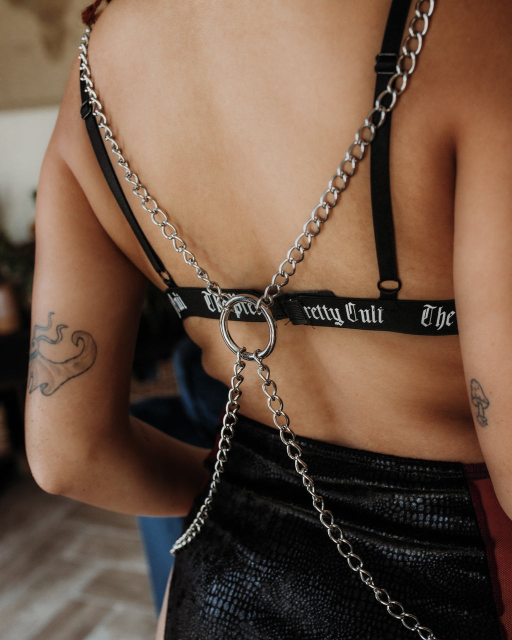 Person wearing a black bra with chain details and 'Pretty Cruel' branding.