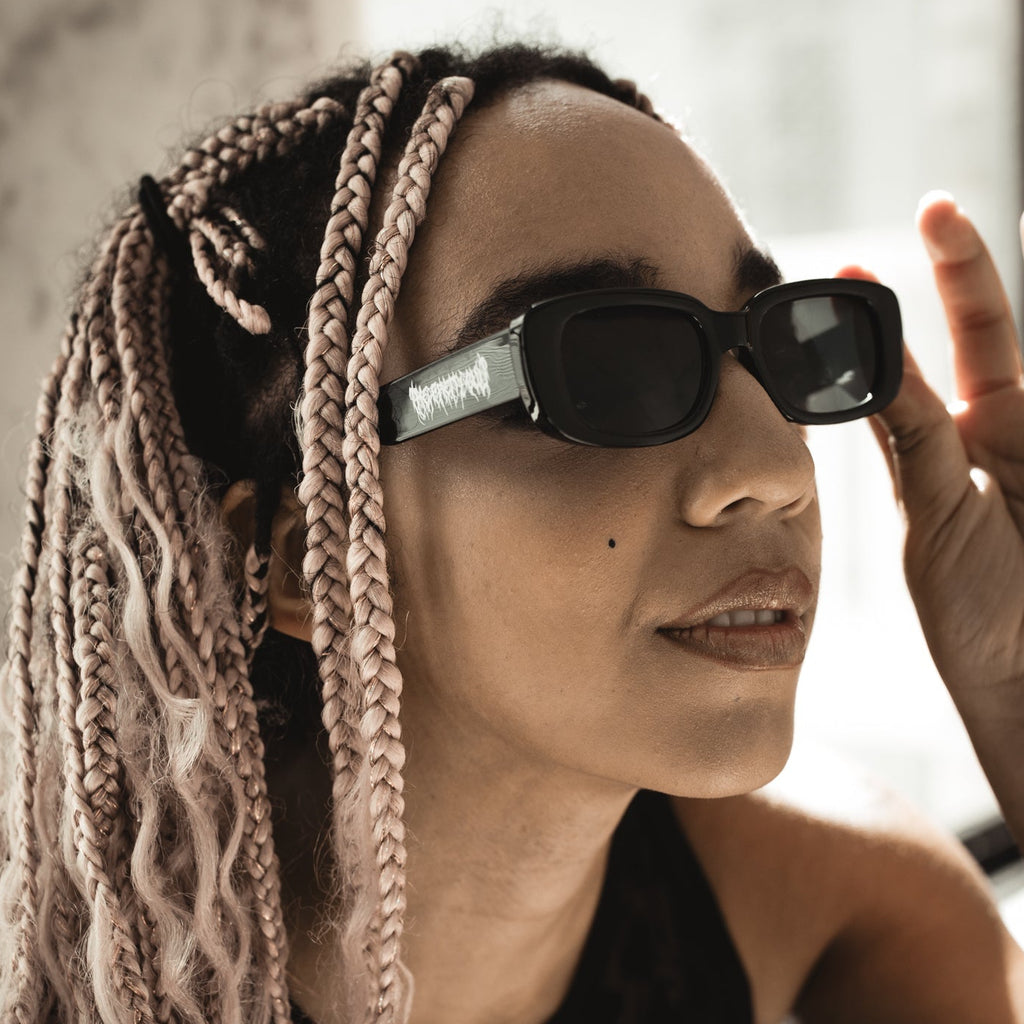 Person with braided hair wearing sunglasses indoors
