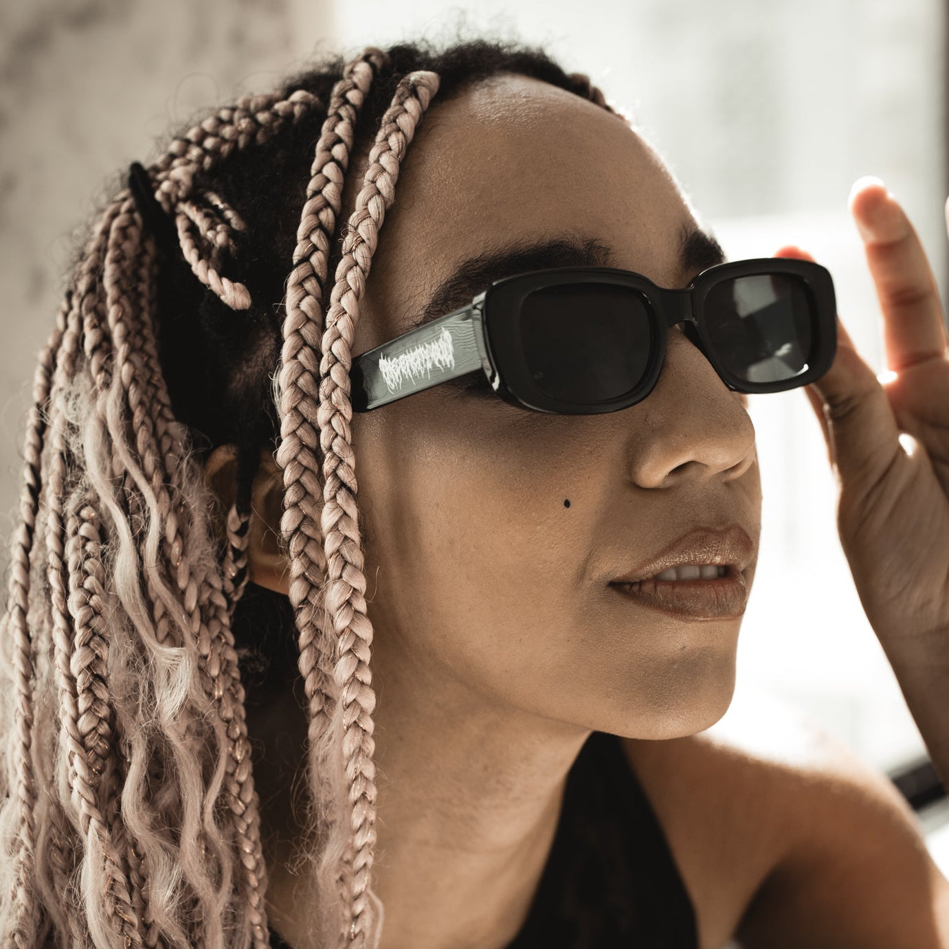 Person with braided hair wearing sunglasses indoors