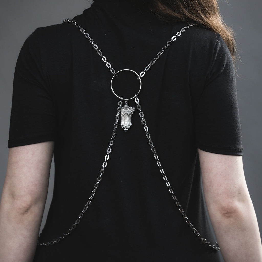 Person wearing a black shirt with a unique necklace design on a gray background