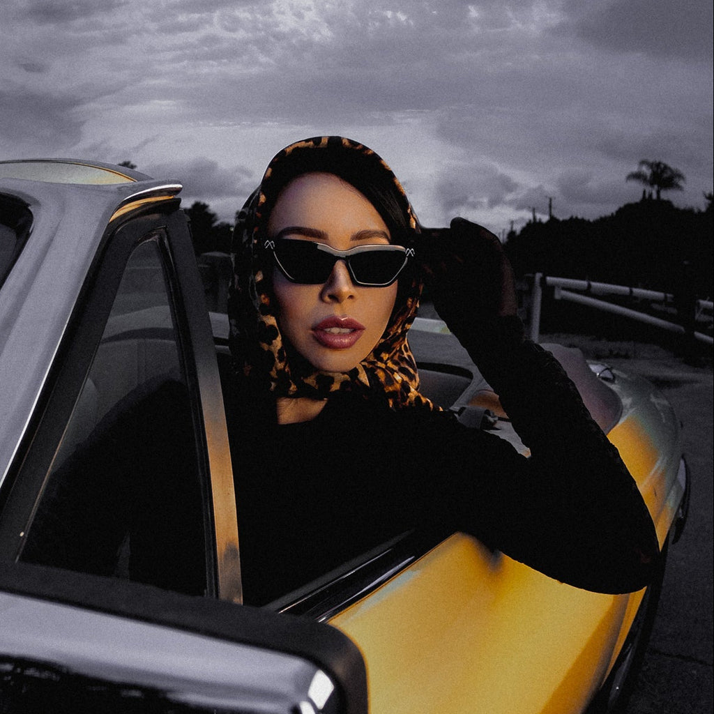 Woman sitting in a yellow car with a dark, cloudy sky in the background