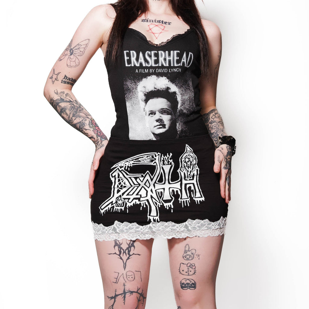 Person wearing a black dress with graphic design and black boots on a white background