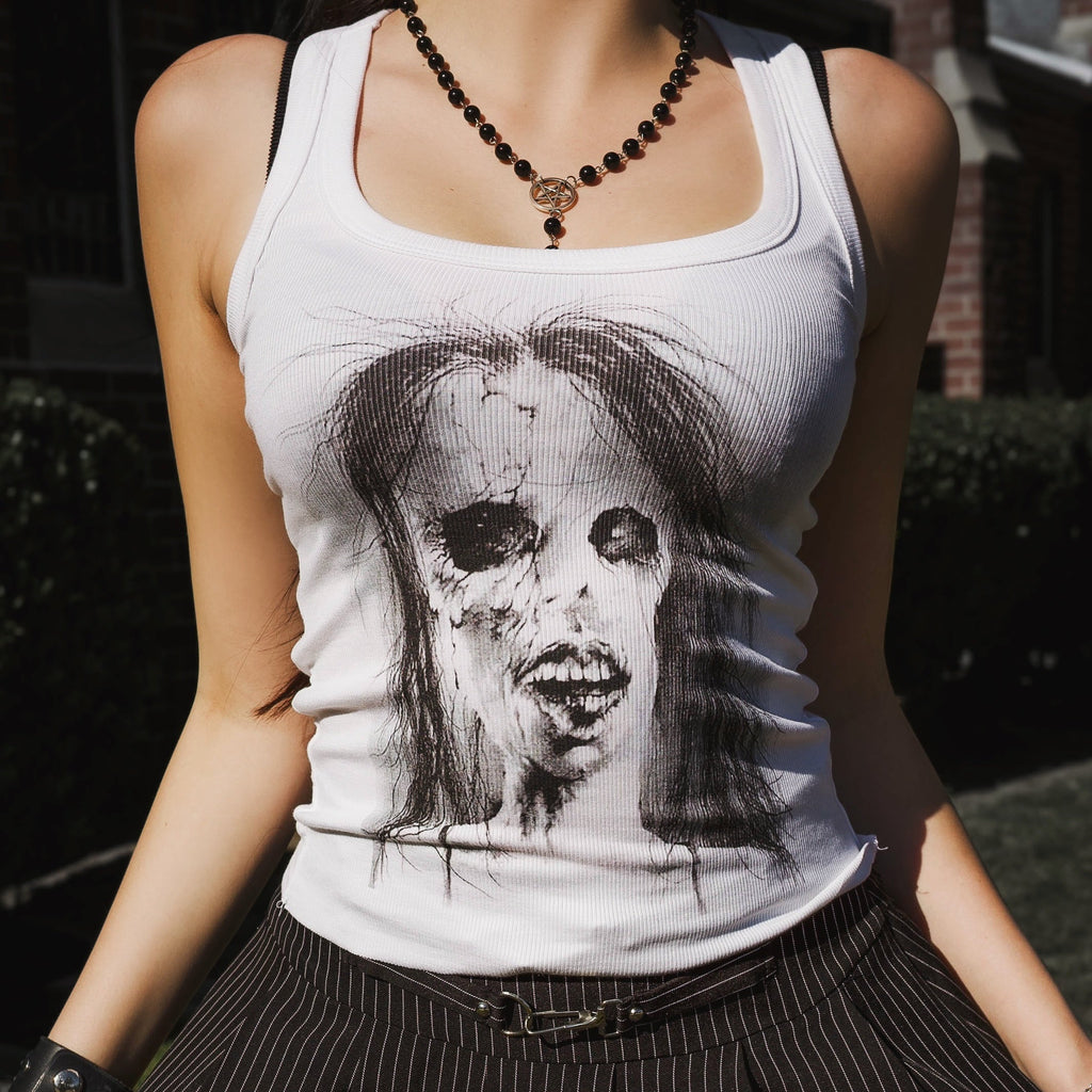 Person wearing a white tank top with a graphic design and a black pleated skirt.