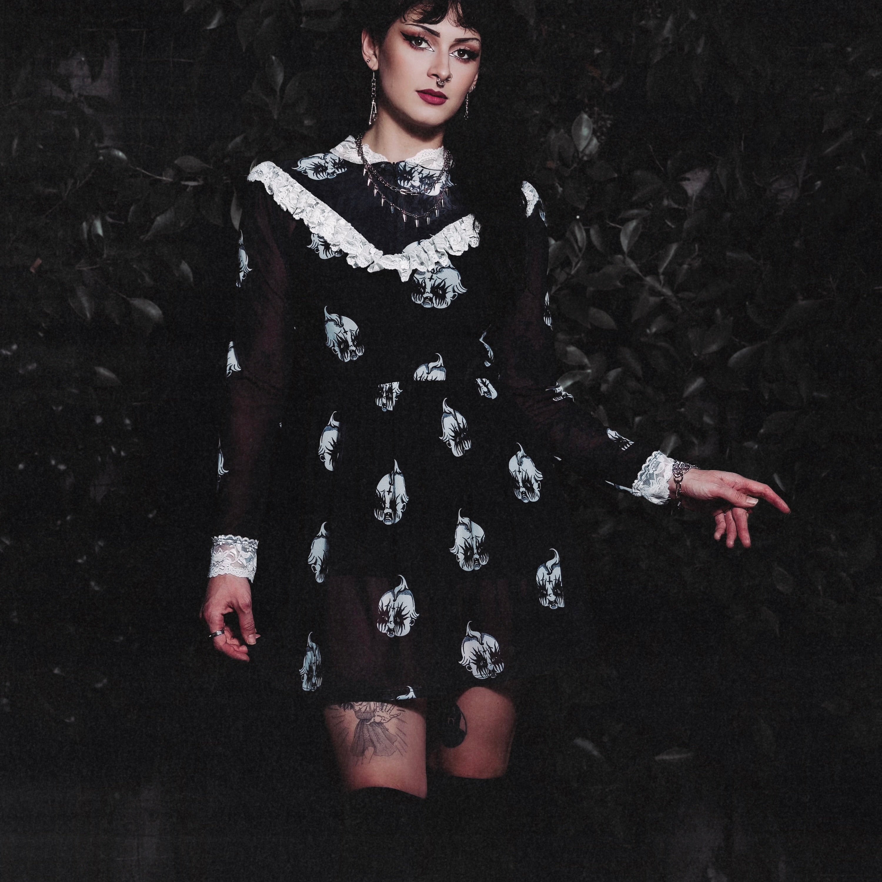 Person wearing a black dress with white patterns against a dark background