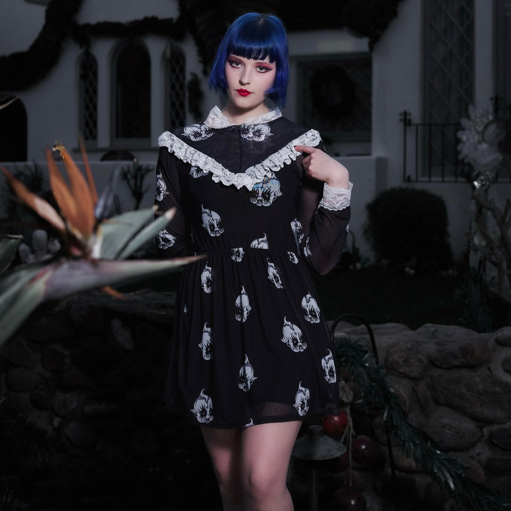 Person wearing a black dress with white patterns in an outdoor setting