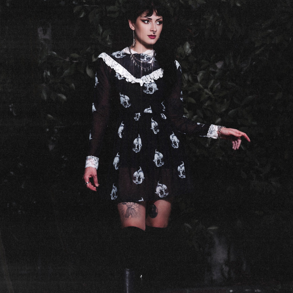 Person wearing a black dress with white patterns against a dark background