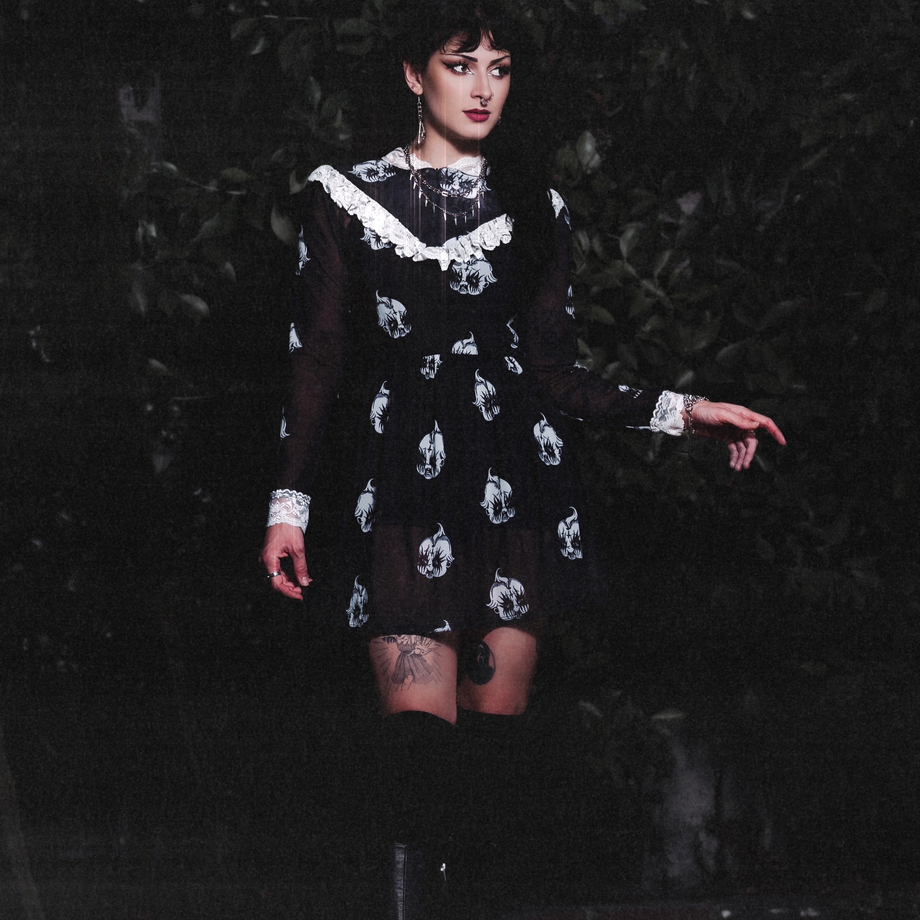 Person wearing a black dress with white patterns against a dark background