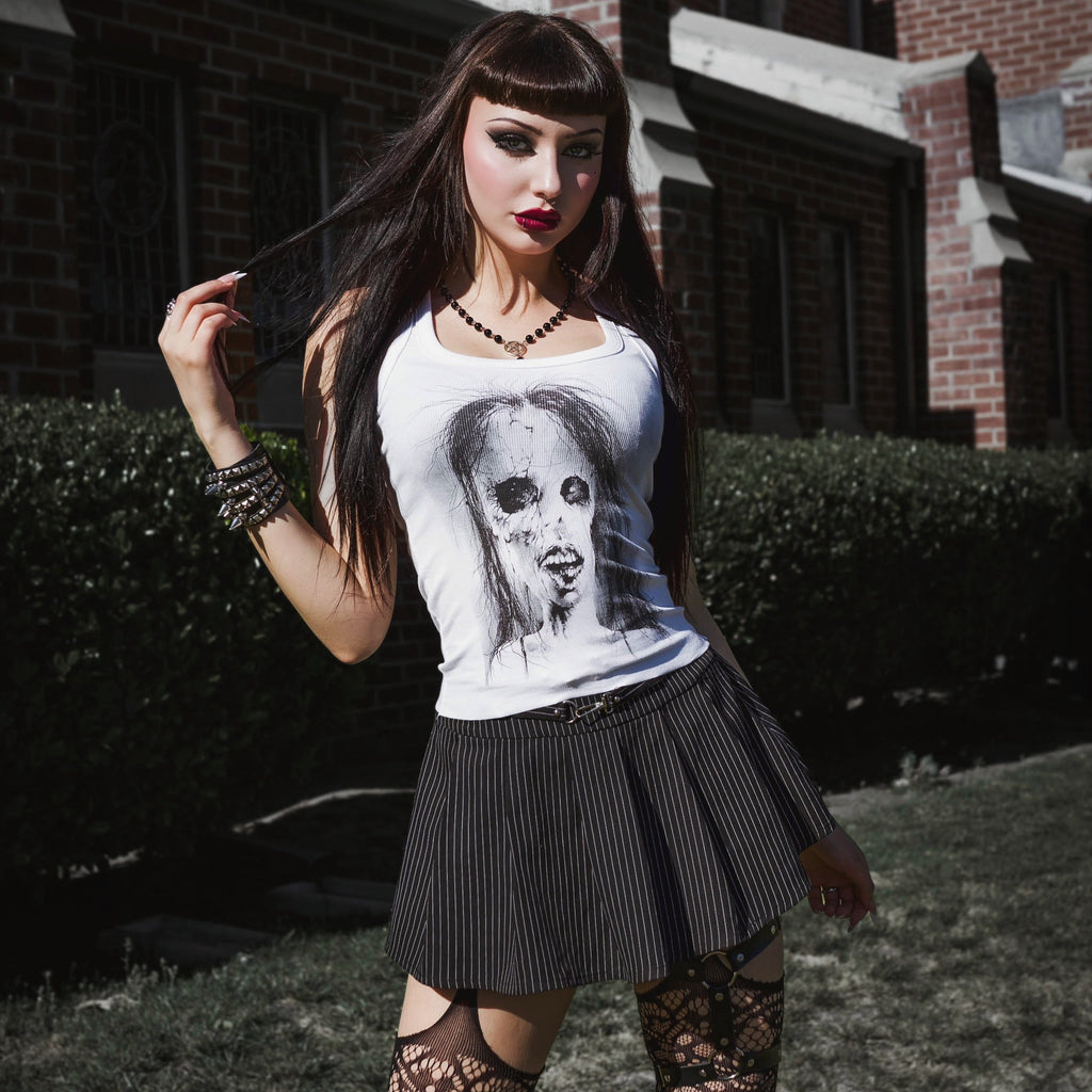 Woman wearing a white t-shirt with a graphic design, black skirt, and lace stockings outdoors.