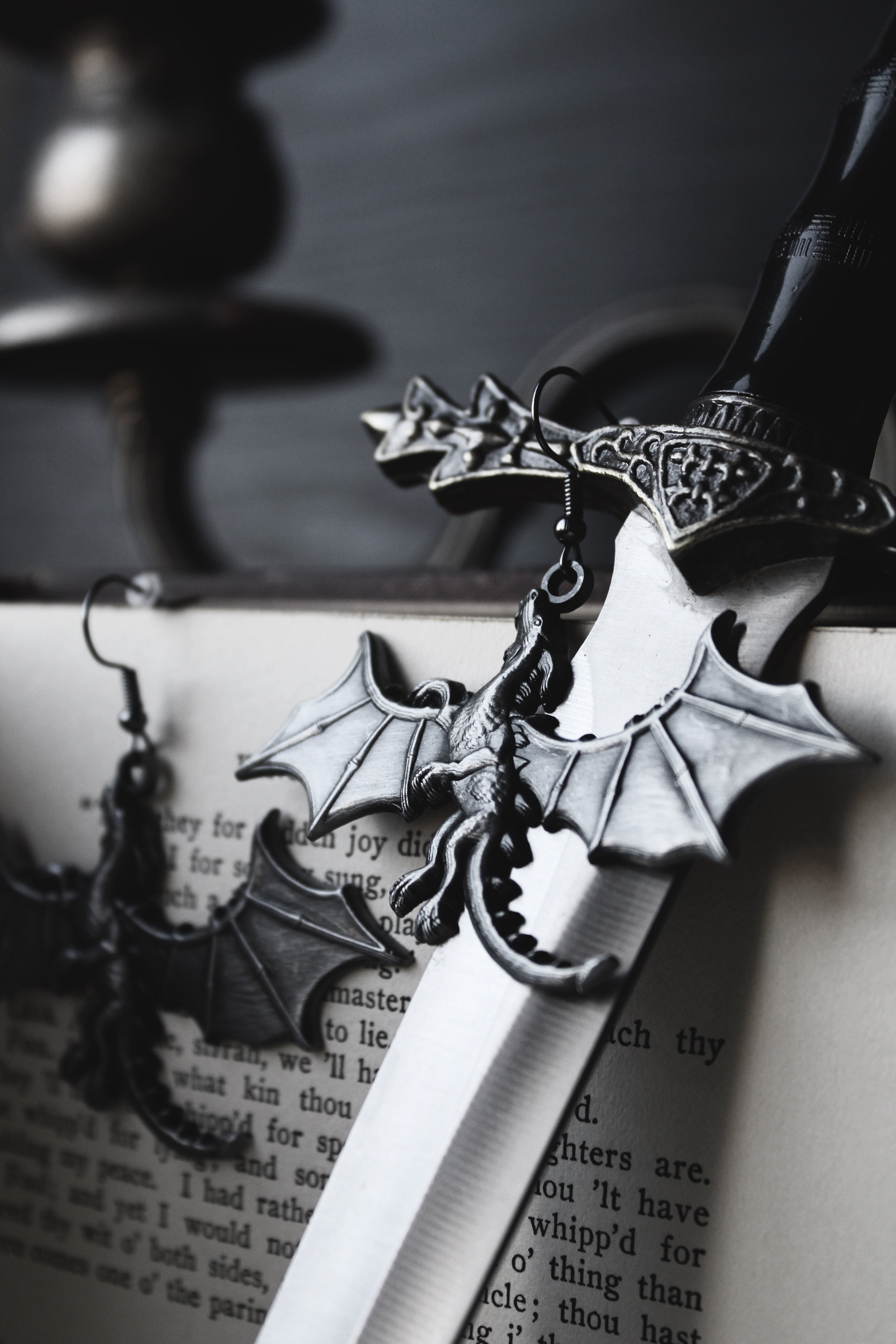 Silver dragon-shaped dagger with detailed hilt on an open book
