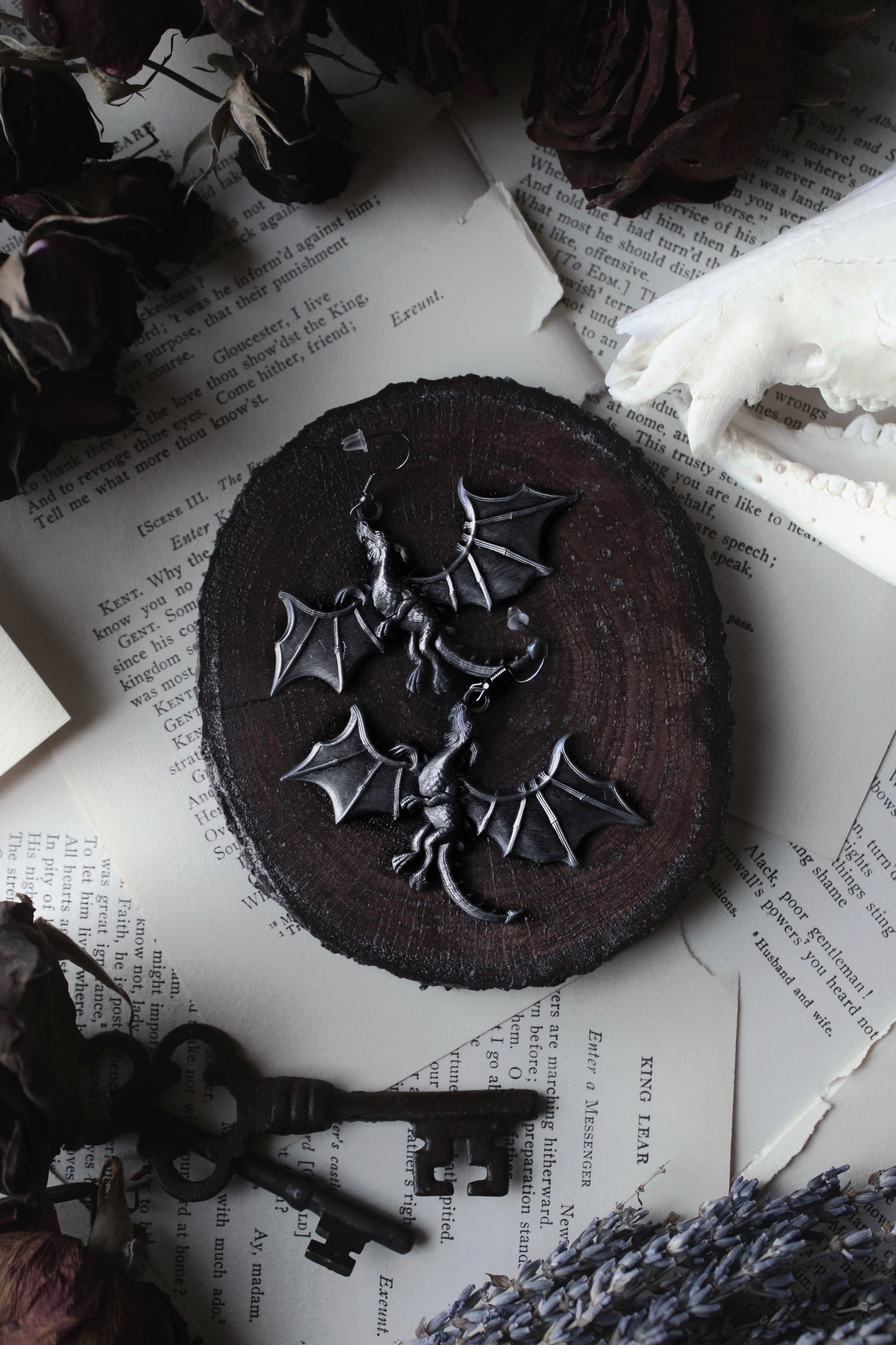 Dark chocolate cookie with a dragon decoration on a textured surface with keys and dried flowers.