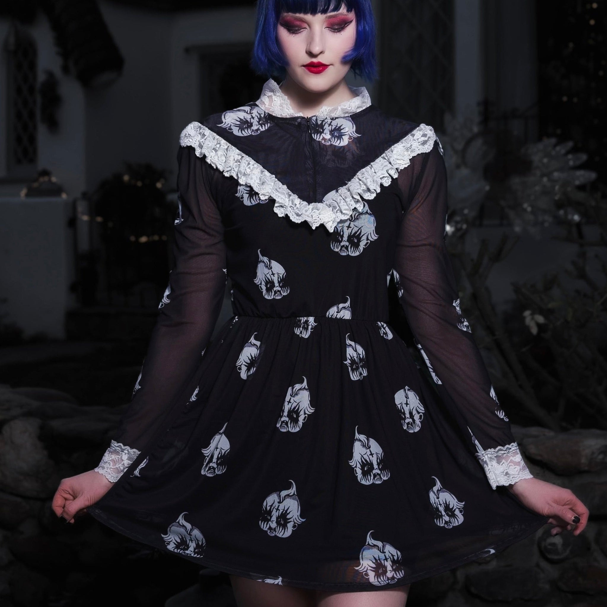 Person wearing a black dress with white patterns in a dark setting