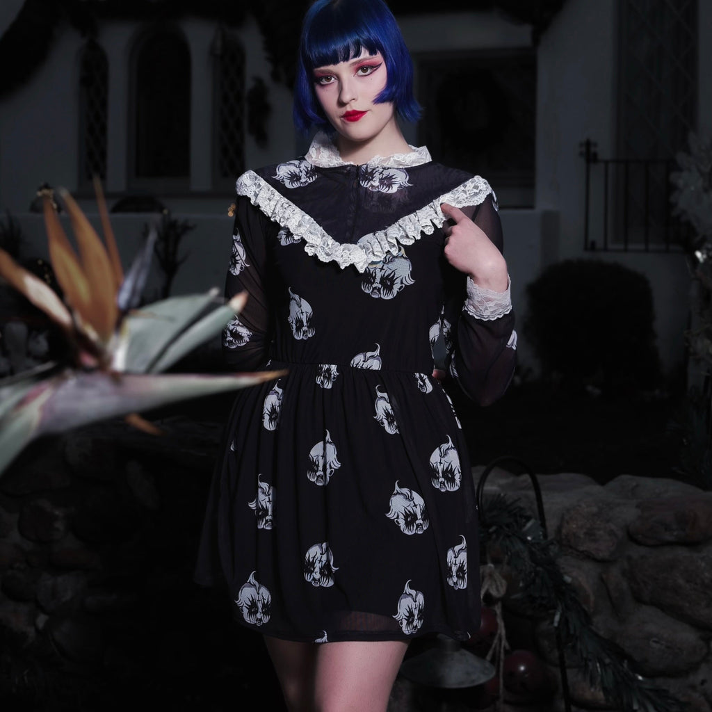 Person wearing a black dress with white patterns in a dark outdoor setting