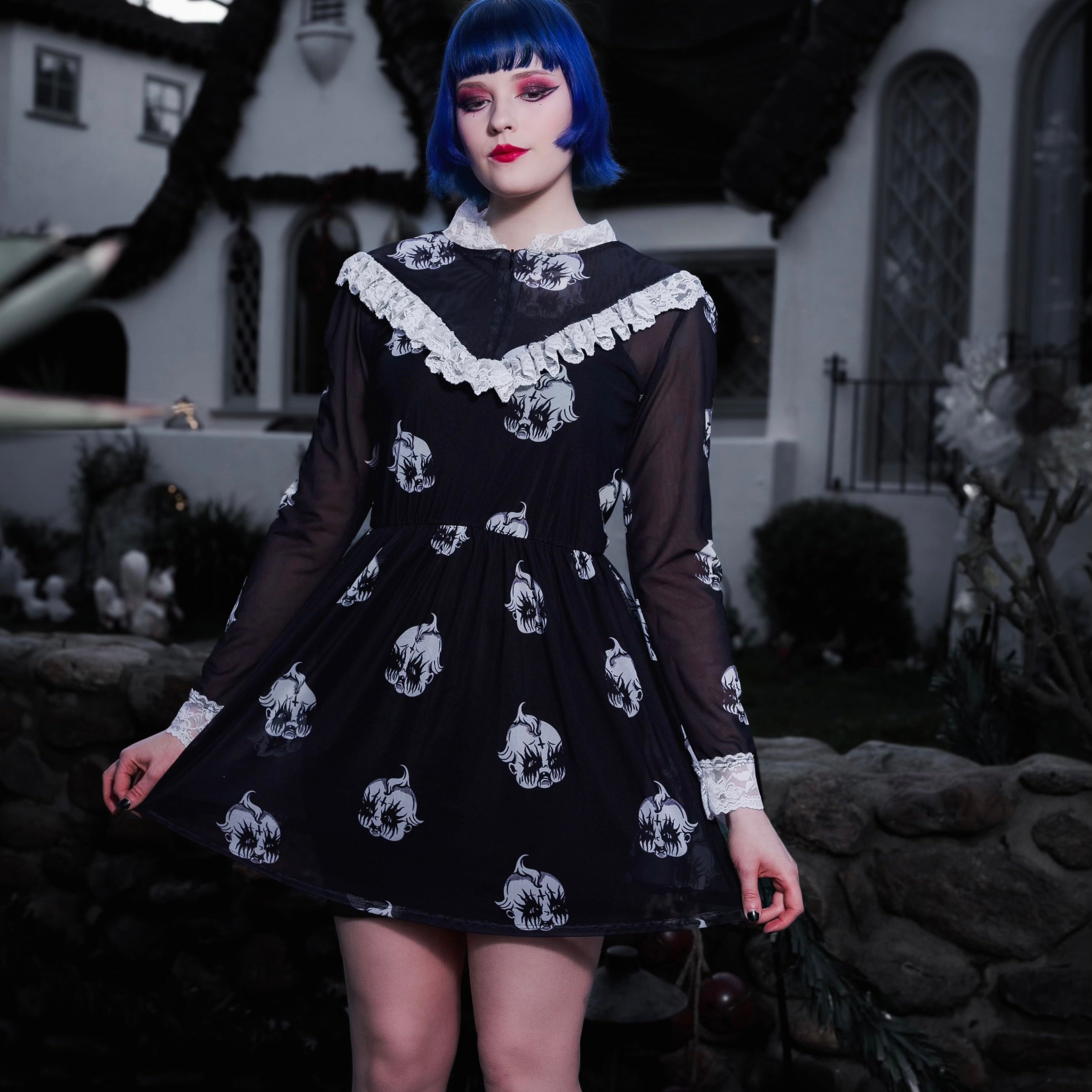 Person wearing a black dress with white patterns in front of a building