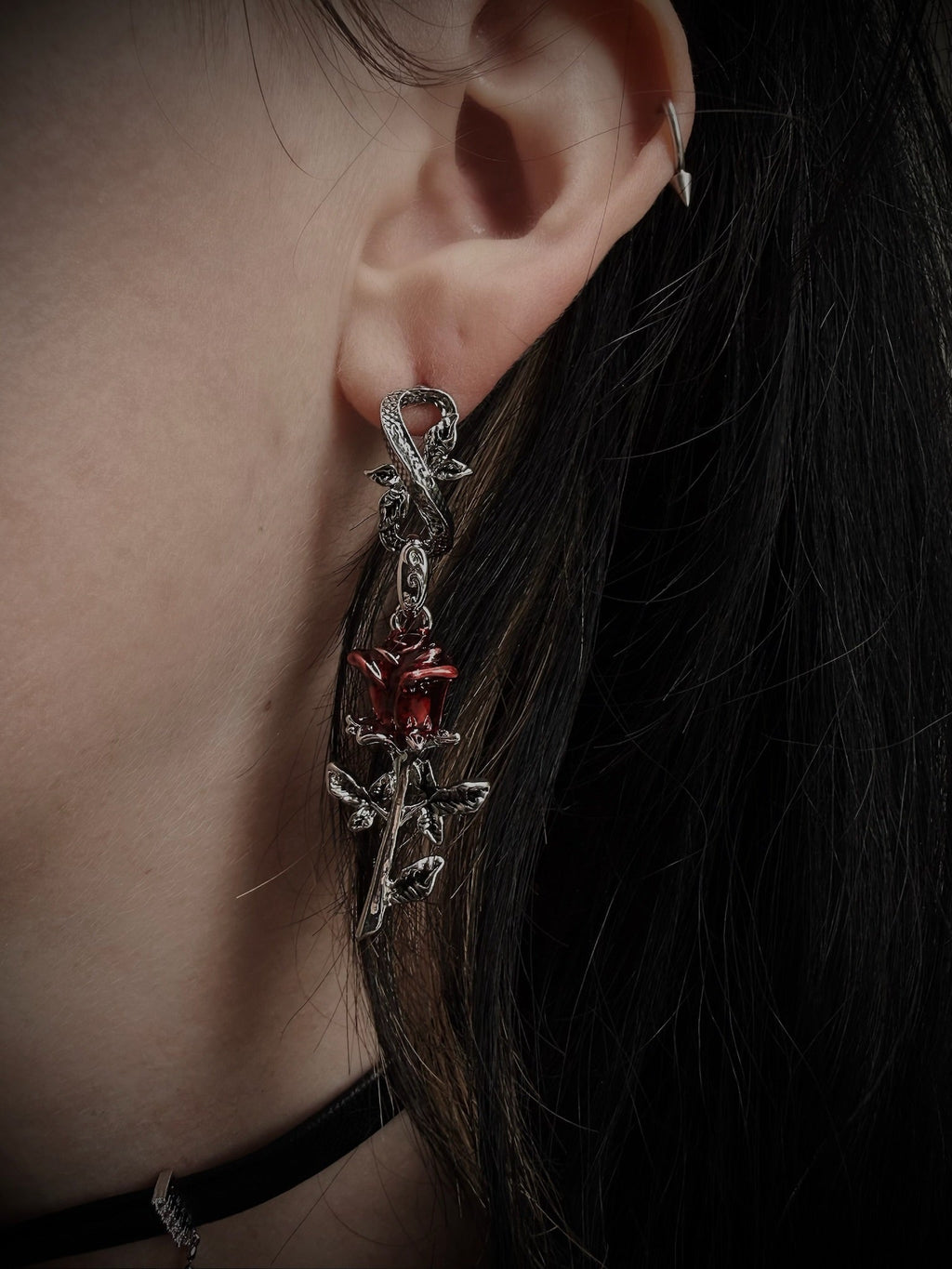 Close-up of an ear wearing a decorative earring with a red gemstone.