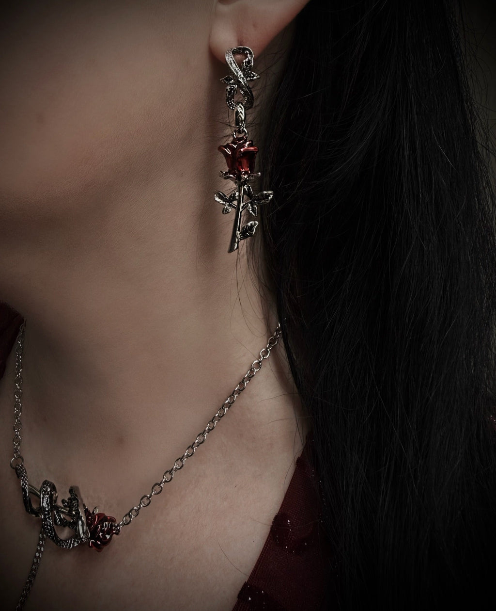 Close-up of a person wearing a detailed silver earring with a red gemstone.