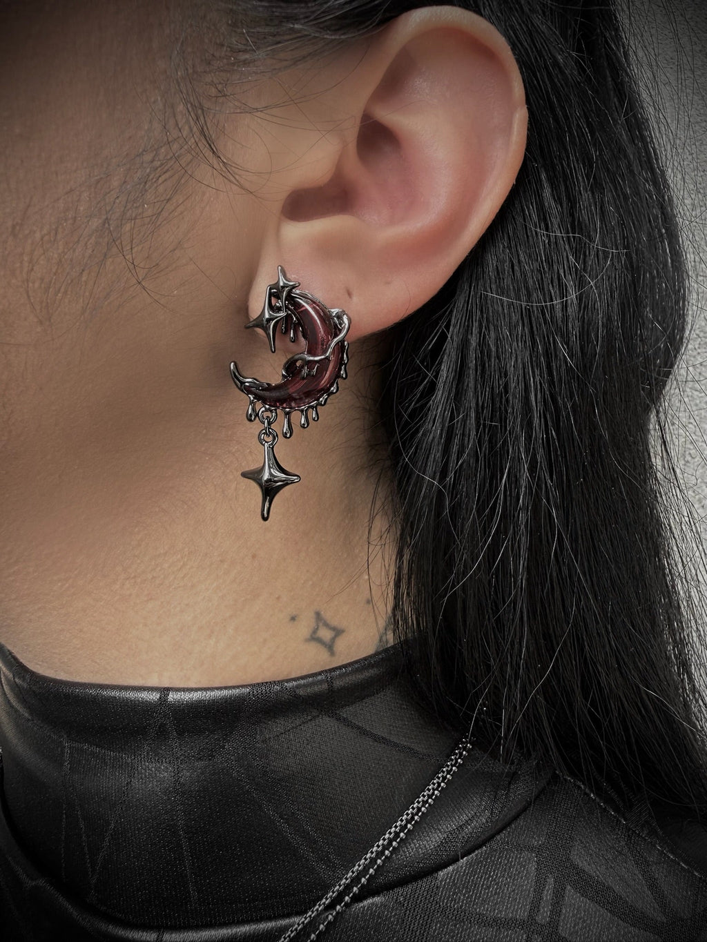 Close-up of an ear with a unique earring featuring a star and crescent moon design.