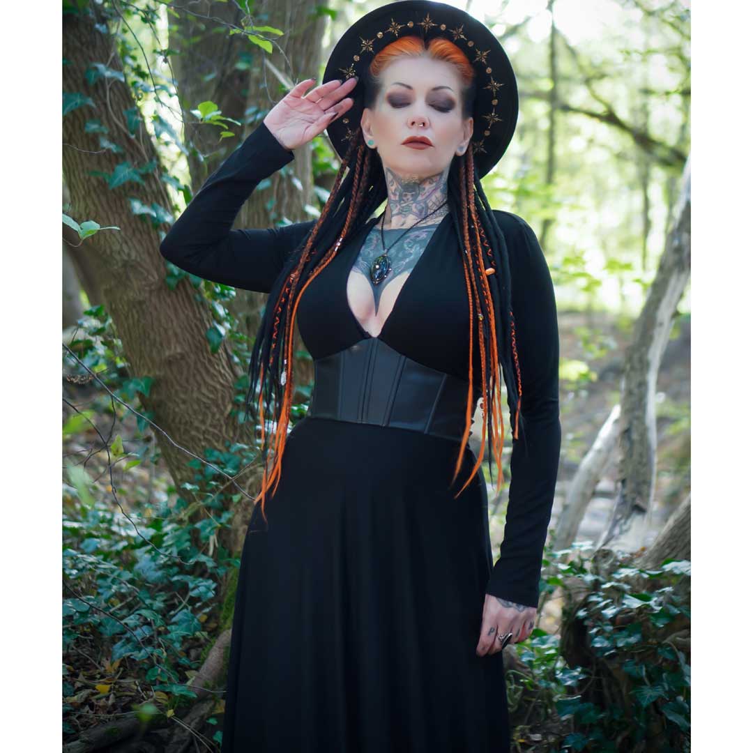 Woman in a black outfit with orange hair standing in a forest