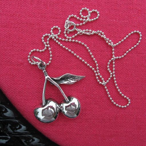 Silver cherry pendant necklace on a pink background