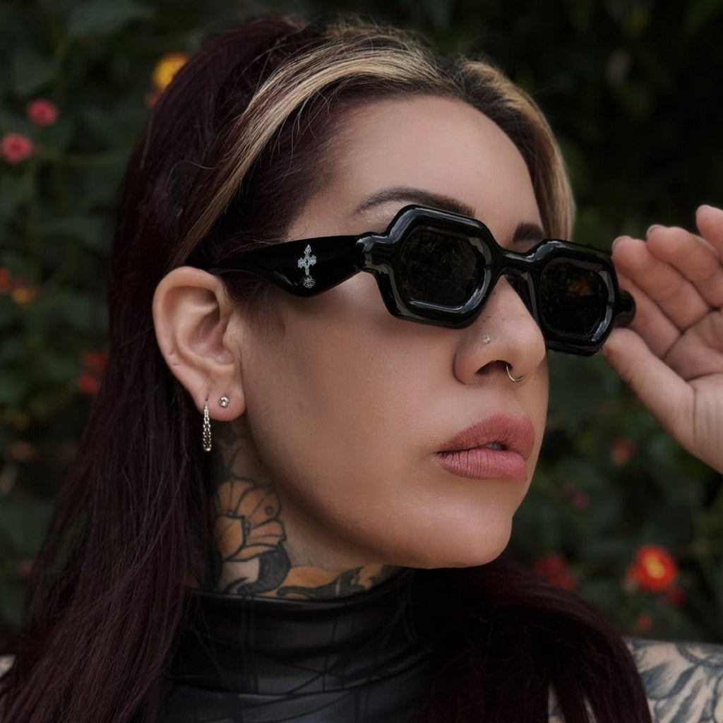 Person wearing black sunglasses with a dark background and floral elements