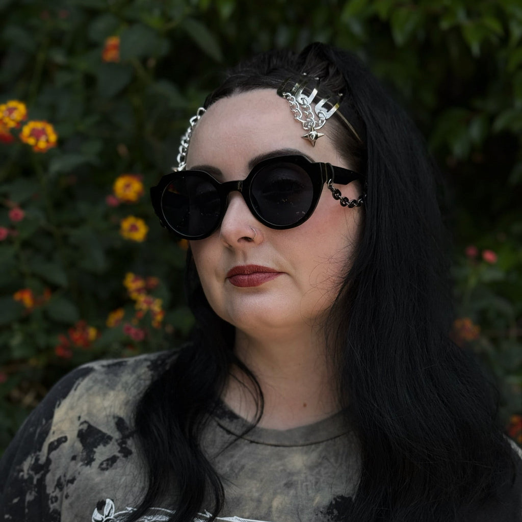 Person wearing dark sunglasses and a decorative headband with a blurred natural background