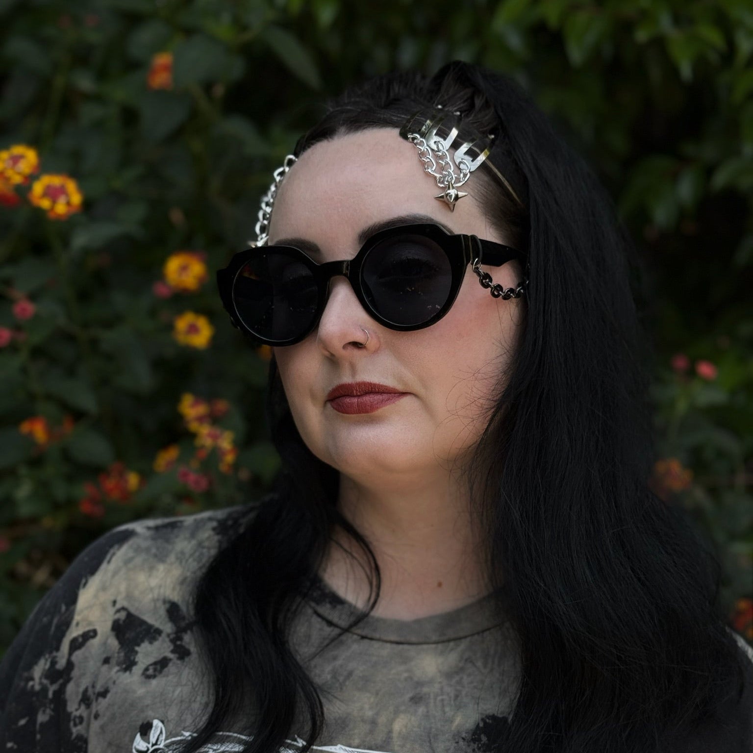 Person wearing dark sunglasses and a decorative headband with a blurred natural background