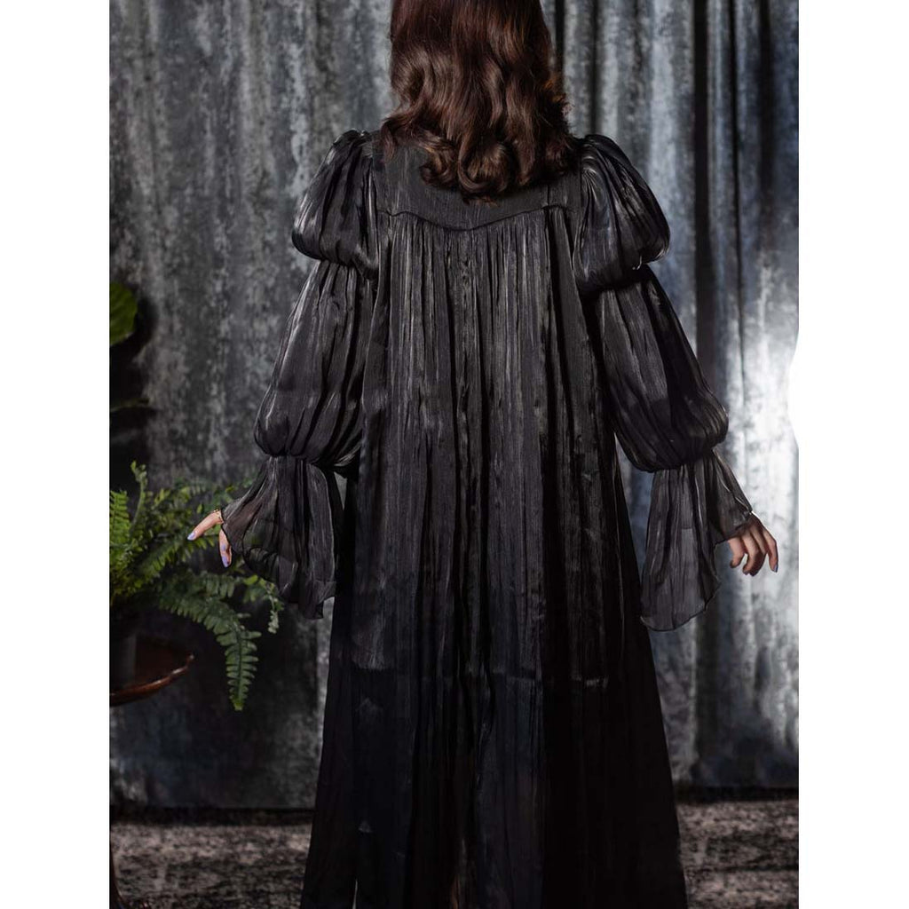 Person wearing a dark, long-sleeve dress with a textured pattern against a gray curtain background.