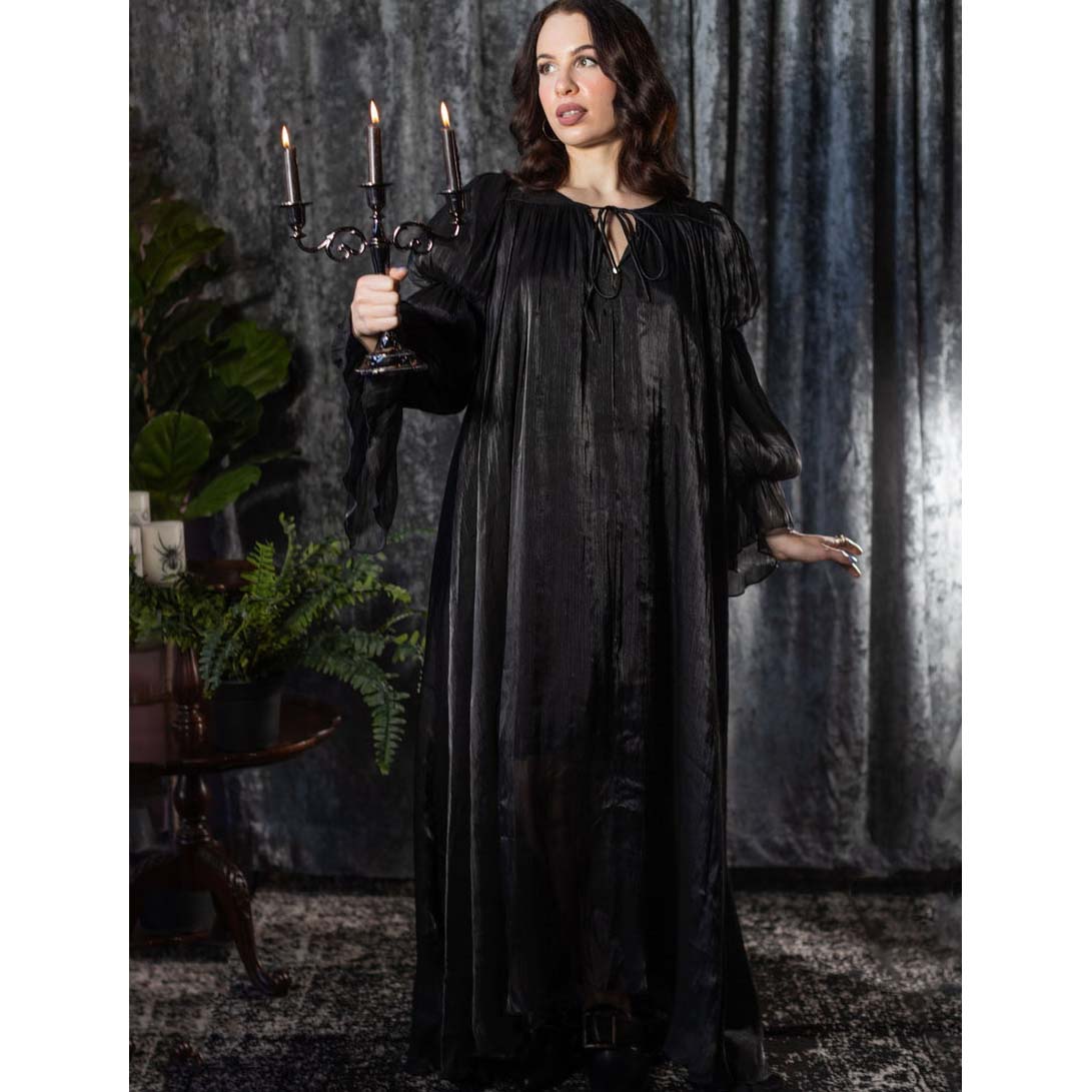 Woman in a long black dress holding a candelabrum in a dark, moody setting.