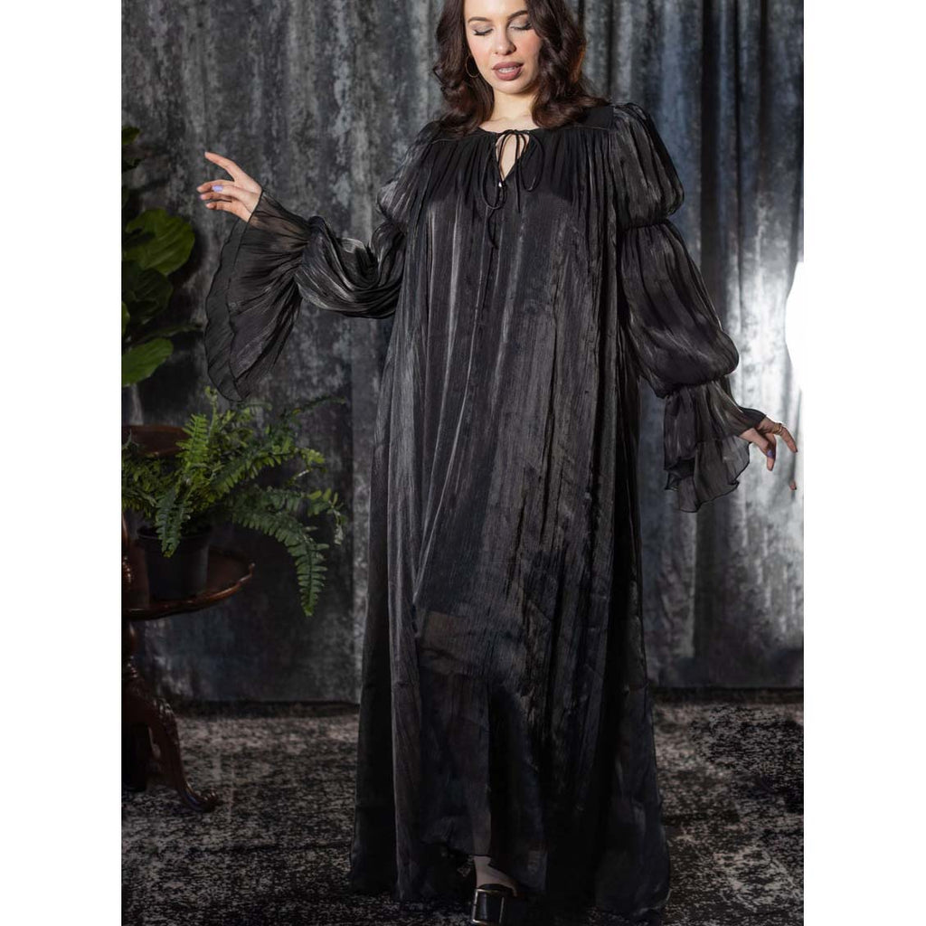 Woman wearing a long black dress with puffed sleeves against a dark background