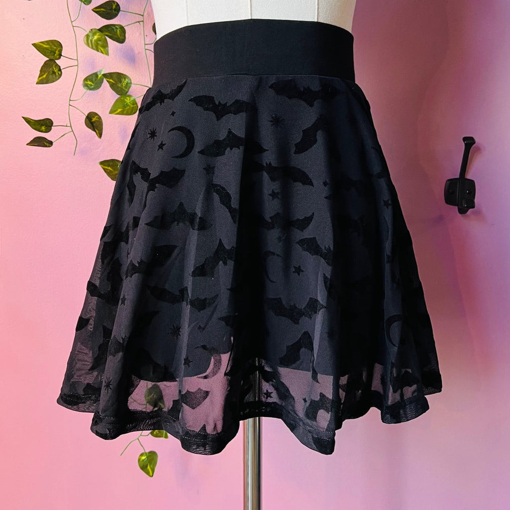 Black skirt with bat pattern on a mannequin against a pink background