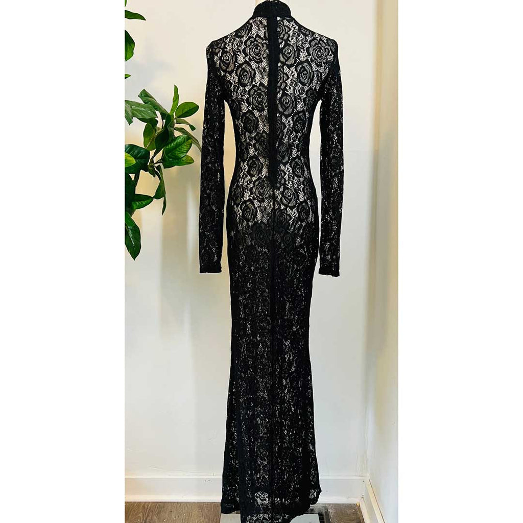 Black lace dress on a mannequin against a white wall with a plant in the background