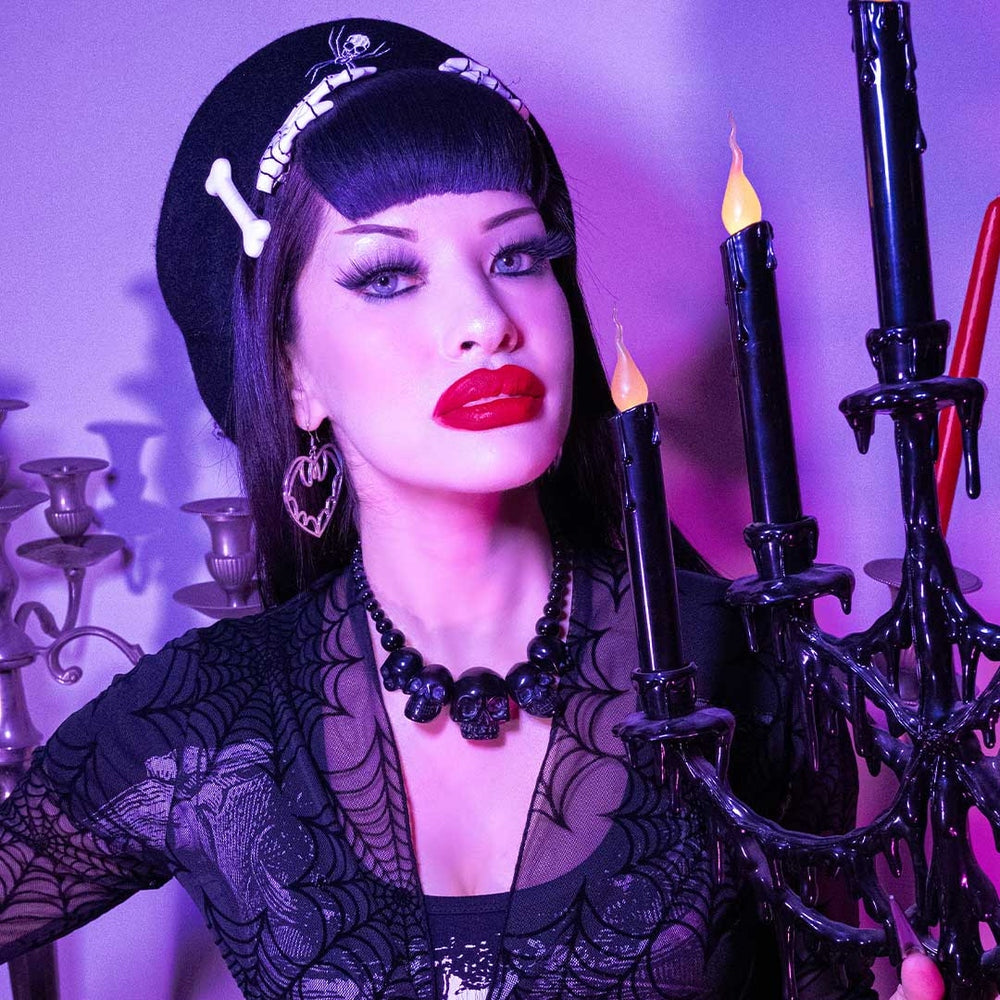 Woman in gothic attire with candles and a purple background