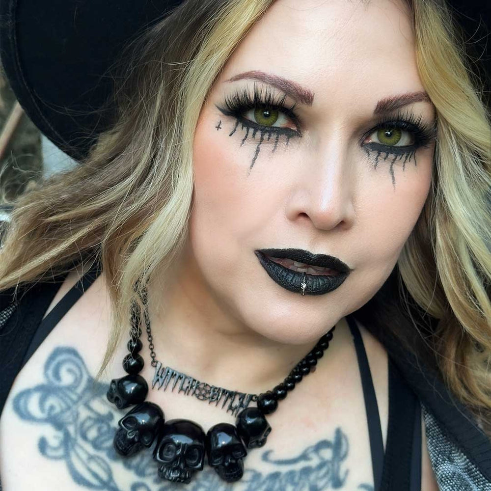 Woman with dramatic makeup and black skull necklace