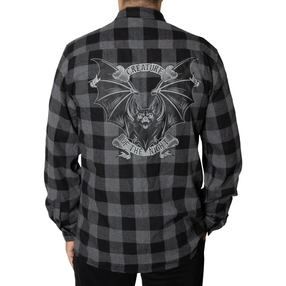 A person shown from the back wearing a long-sleeve black and gray buffalo plaid flannel shirt with a large bat graphic and the words 'CREATURE OF THE NIGHT' printed across the back.