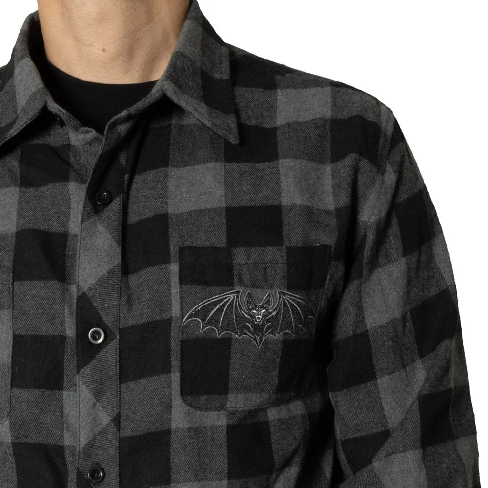 Close up pic of a black and gray flannel button up collared shirt with a gothic bat on the chest pocket.