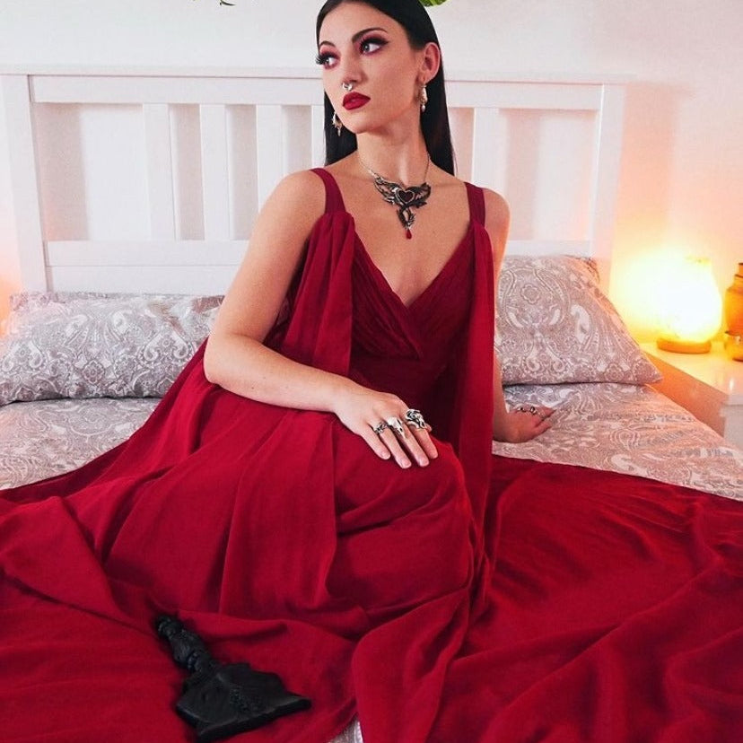 Woman in a red dress sitting on a bed with a warm and cozy atmosphere.