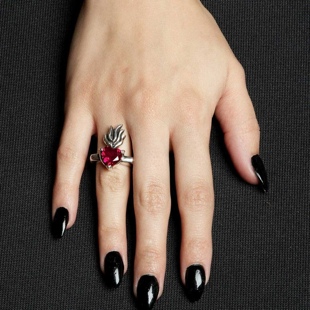 Silver ring with a red heart-shaped gemstone on a white background