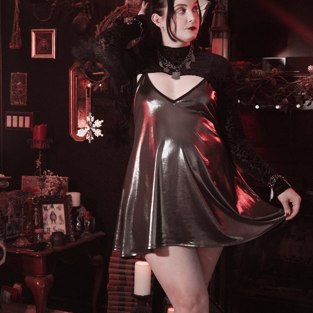 Person wearing a black leather dress in a dark, ornate room with candles and decorative items.