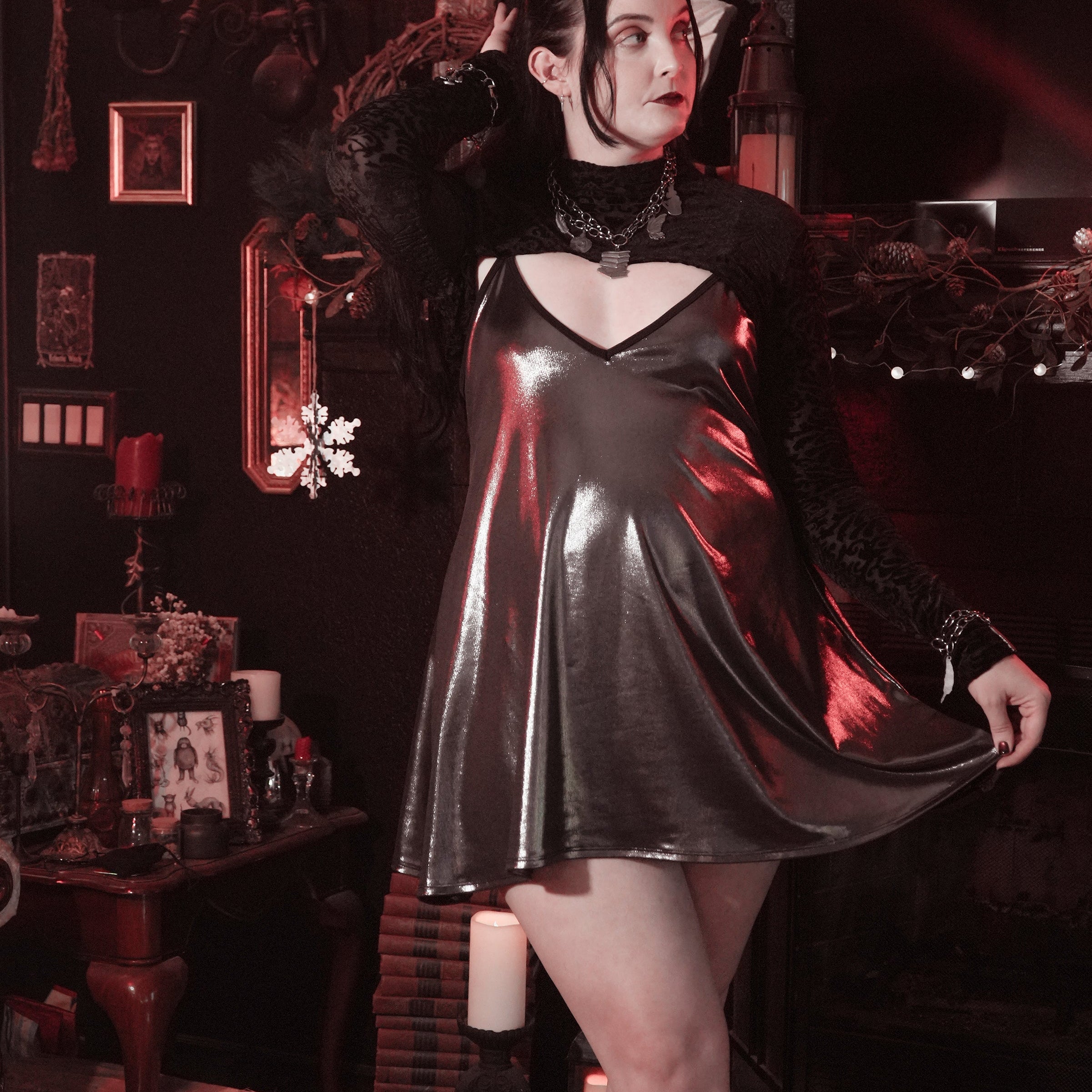 Person wearing a black leather dress in a dark, ornate room with candles and decorative items.