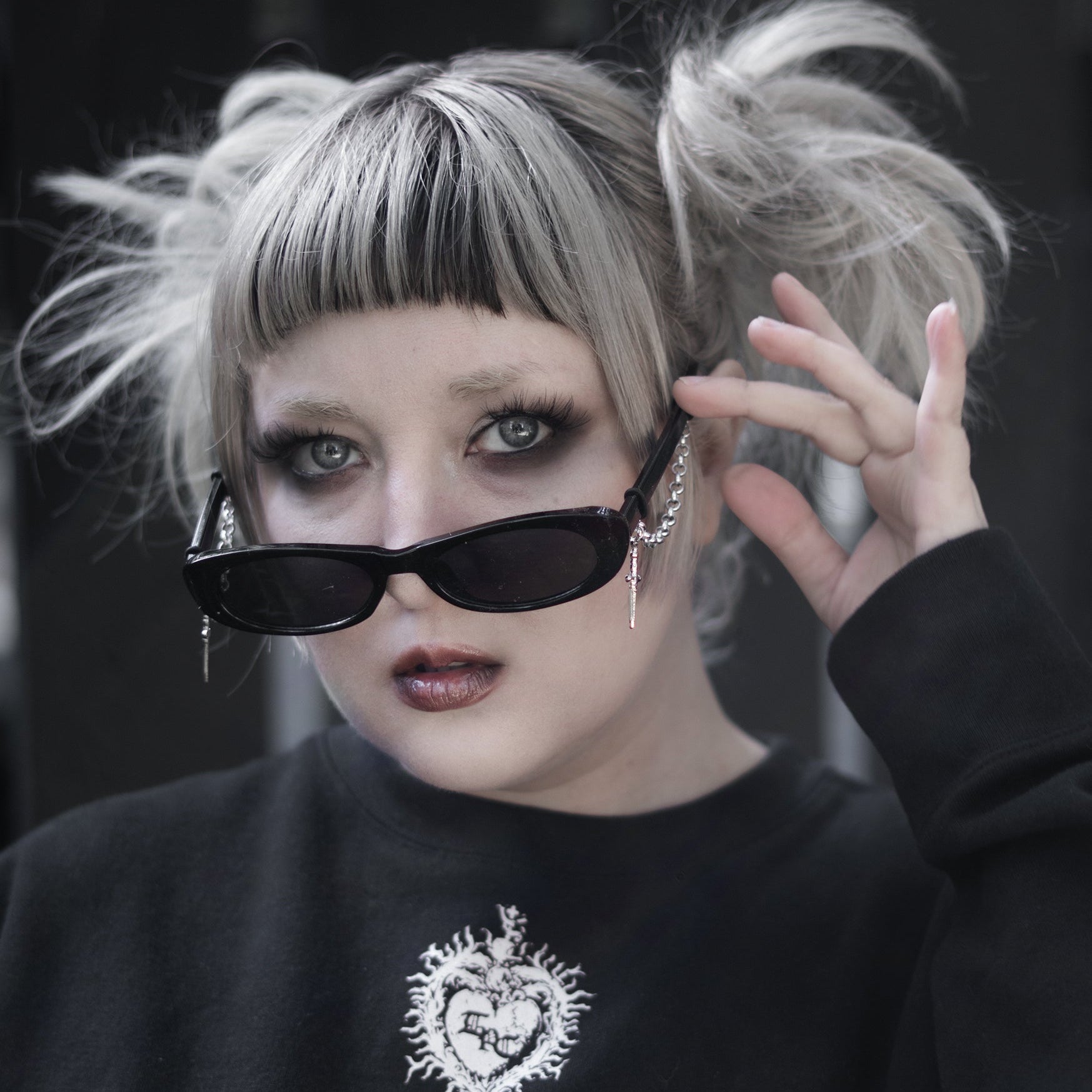 Person with styled hair and dark sunglasses against a black background