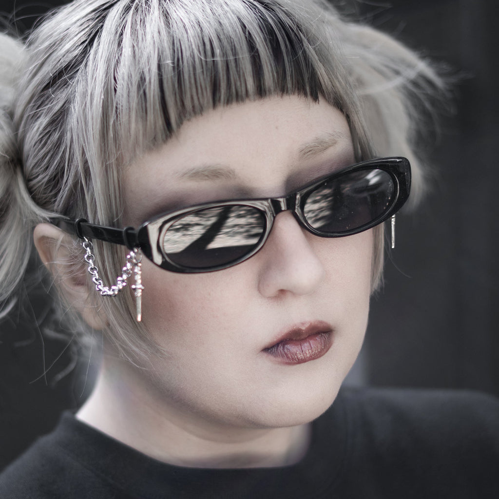Person with blonde hair and sunglasses wearing a black shirt with a white design.