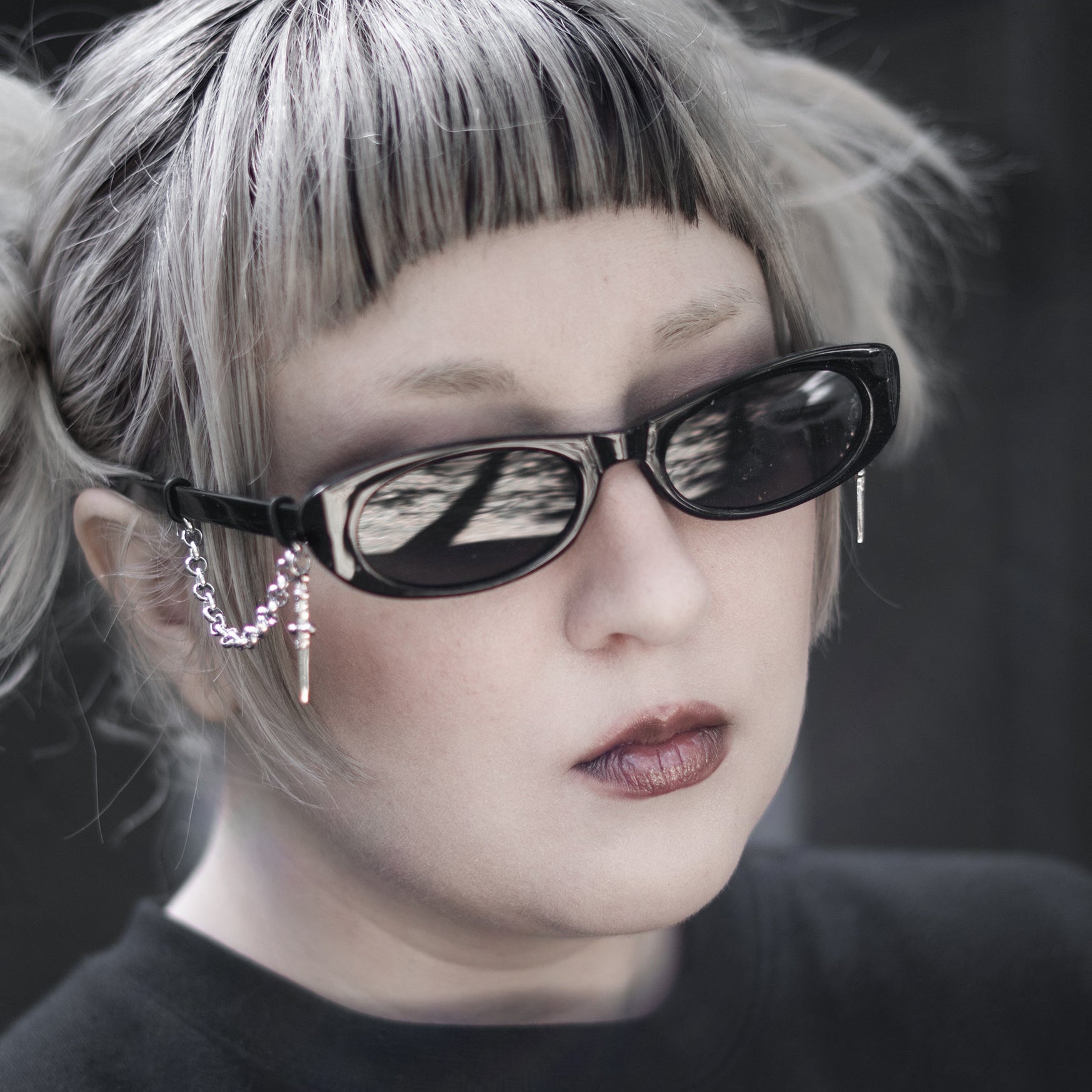 Person with blonde hair and sunglasses wearing a black shirt with a white design.