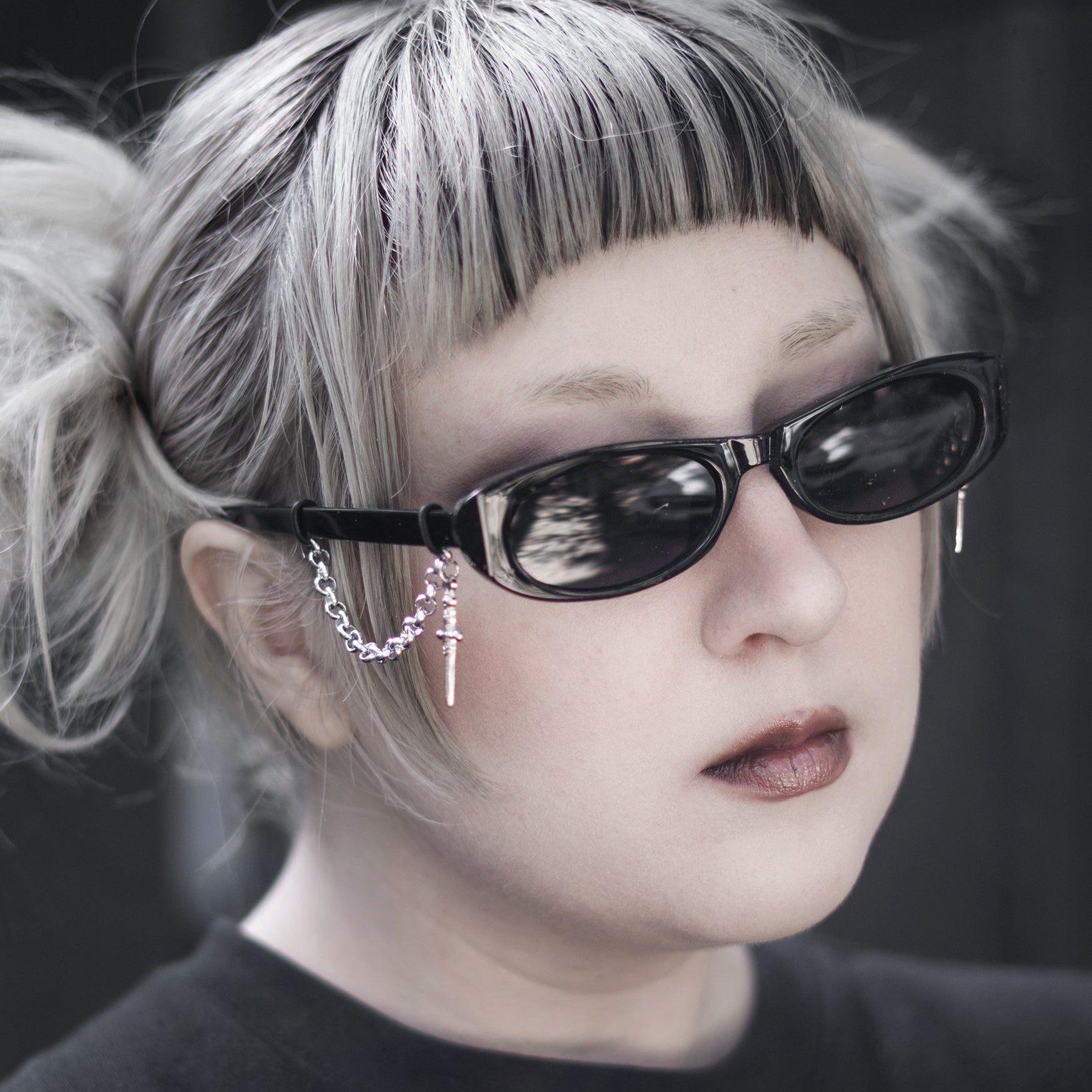 Person with blonde hair and sunglasses wearing a black shirt with a white design.