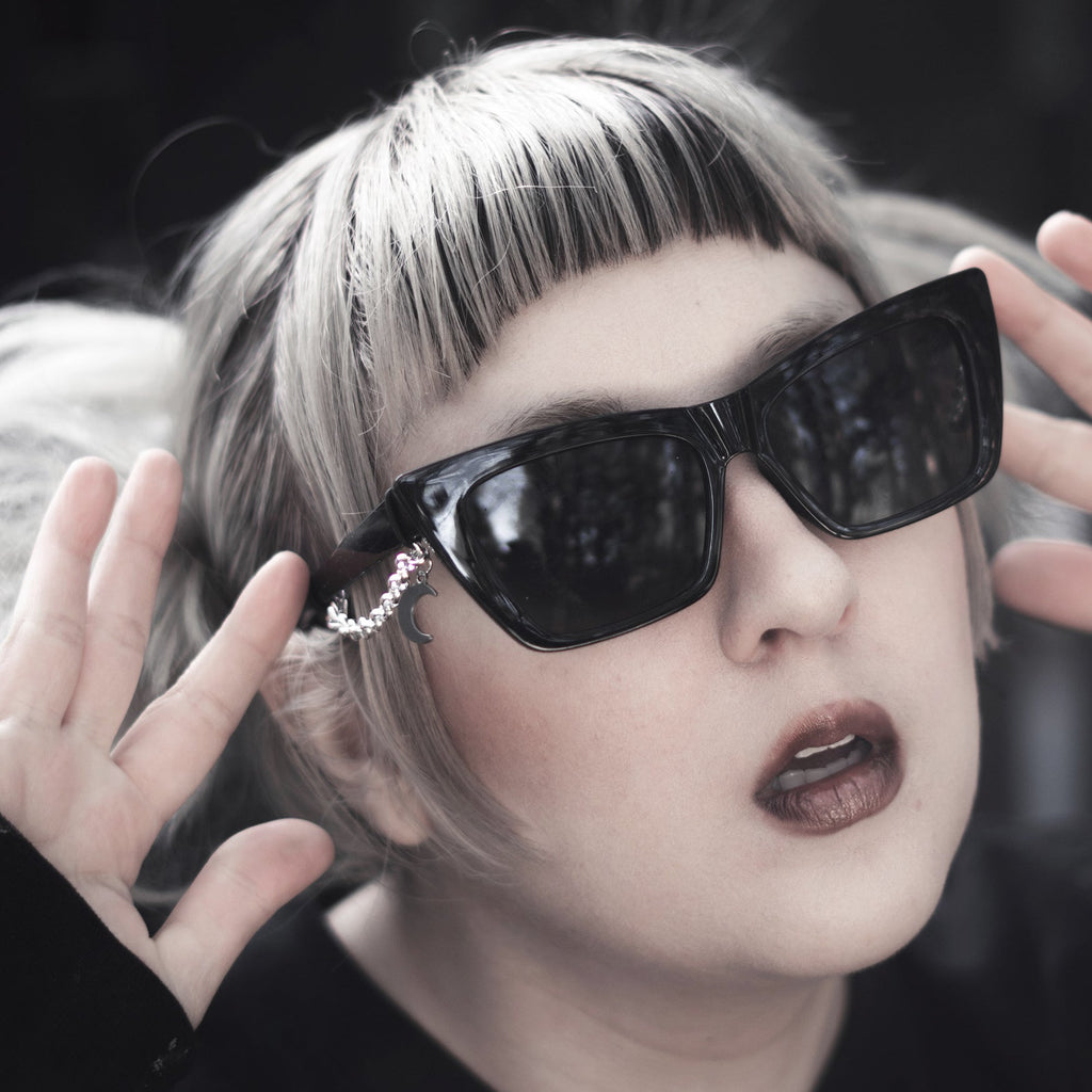 Person wearing large black sunglasses with a dark background