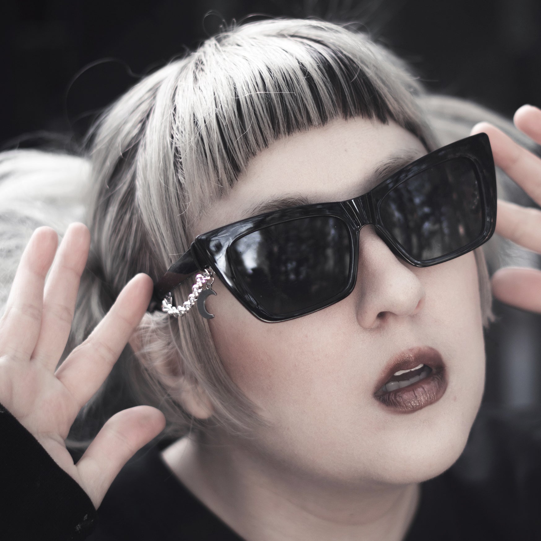 Person wearing large black sunglasses with a dark background